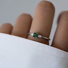 Sweet, simple, and dainty emerald ring. Perfect for a minimalist look, or for stacking. It adds a fun pop of color to your look! Featuring a cushion cut stone with pear stones adorning both sides - making this a delicate and beautiful ring!Emerald rings are said to represent luck, love, peace, and hope. Made of 925 Sterling Silver Available in 14k Gold or Rhodium Plating We use a THICK 14k Gold plating - for a piece that will last you years to come! VERY HIGH QUALITY Made of the highest grade of Emerald Ring Simple, Emerald Ring Design, Silver Promise Rings, Silver Emerald Ring, Dainty Engagement Rings, Emerald Wedding Rings, Emerald Rings, Minimalist Engagement Ring, Green Stone Rings