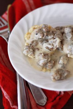 a white plate topped with meatballs covered in gravy next to a fork