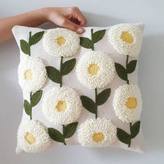 a hand holding a pillow with flowers on it