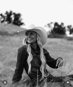 a woman wearing a cowboy hat sitting in the grass