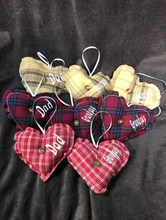 four plaid heart ornaments are arranged on a black sheet with the word mom written on them