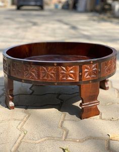 a wooden bowl sitting on top of a stone floor next to a parking lot with cars parked in the background