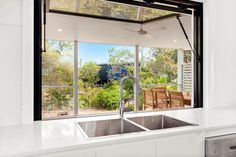 a kitchen with a sink and window looking out onto the garden outside in front of it