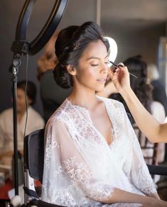 a woman is getting her make up done in front of a mirror and lighting equipment