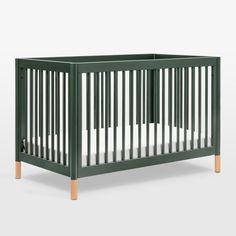 a green crib with white sheets and wood trims on the sides, in front of a gray background