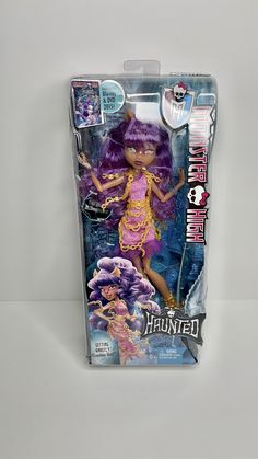 the doll has purple hair and is wearing a pink dress