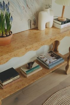 a wooden table topped with books next to a lamp