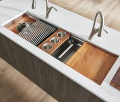 a kitchen sink with wooden drawers and stainless steel faucets in the bottom drawer