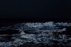 the ocean is dark and choppy at night, with waves coming in to shore