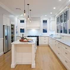 a large kitchen with white cabinets and wood floors