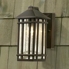 a light that is on the side of a wall next to a wooden building and grass