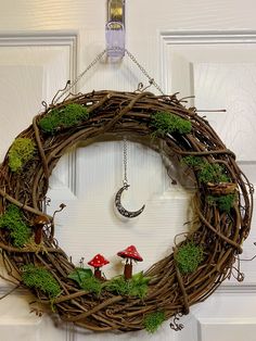 a wreath with moss and mushrooms hanging from the front door, decorated with a crescent