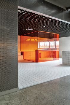 an empty room with tiled floors and walls in the center is lit by orange lights