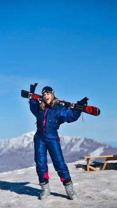 a woman holding skis on her shoulders in the snow