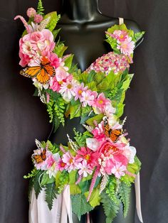 a mannequin with pink flowers and butterflies on it's chest, in front of a black background