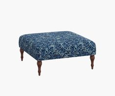 a blue ottoman sitting on top of a white floor next to a wooden leg rest