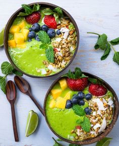 two bowls filled with green smoothie topped with fruit