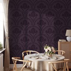 a dining room with a table and chairs in front of a wallpapered background