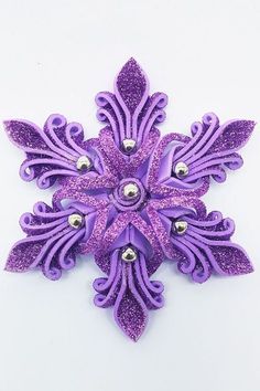 a purple snowflake with lots of silver balls in it's center on a white surface