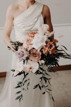 a woman in a white dress holding a bouquet of pink and orange flowers on her wedding day