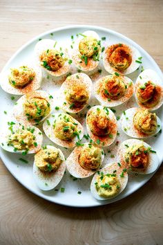 deviled eggs on a white plate topped with chives and seasoning sprinkles