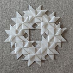 an origami piece is arranged in the shape of a star on a gray surface