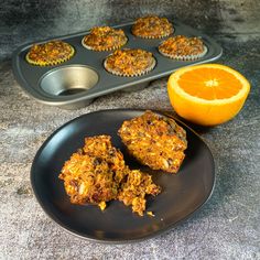 muffins and an orange on a plate next to a muffin tin tray