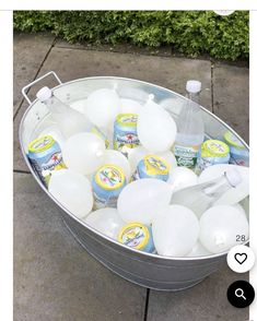 a bucket filled with lots of bottles of water next to a sidewalk on top of cement