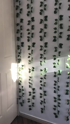 green leaves are growing on the wall next to a white door with light coming through it