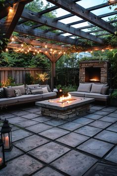 an outdoor living area with couches, fire pit and string lights on the ceiling