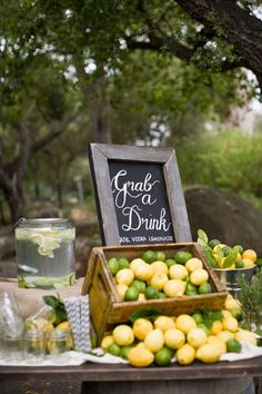 a table topped with lemons and limeade next to a chalkboard sign