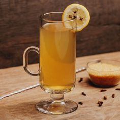 a glass cup filled with liquid next to a sliced lemon