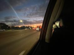 the sun is setting behind some cars on the road with traffic lights in the distance