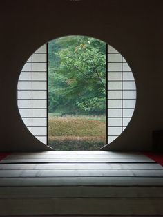 an empty room with a circular window on the wall and grass in the yard behind it