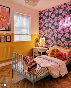 a bed room with a neatly made bed and a neon sign above the headboard