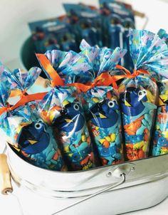 a bunch of toothbrushes wrapped in plastic and tied with orange ribbon sitting in a metal container