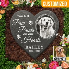 a heart shaped memorial stone with a dog's photo on it and flowers in the background