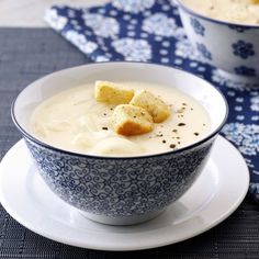 two bowls filled with soup and croutons on top of a table next to each other