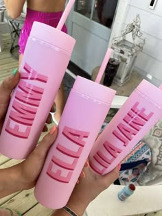 three pink tumblers with the words drink me written on them, in front of a woman's face