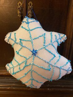 a white and blue decorative pillow hanging on a door