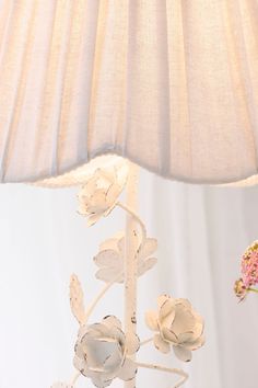 a table lamp with flowers on it next to a flower vase and a white wall