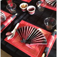 a table topped with red plates and cups filled with different types of food next to utensils