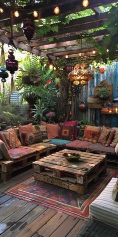 an outdoor living area with couches, tables and lights hanging from the rafters