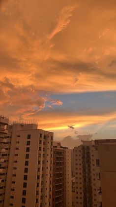 the sun is setting over some buildings in this cityscape, with tall buildings and balconies on either side