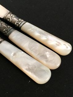 three white jade chopsticks with black handles on a black tableclothed surface