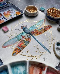 a dragonfly painted on paper next to other paints