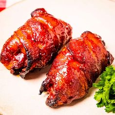 two pieces of meat sitting on top of a white plate next to some parsley