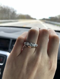 a woman's hand on the steering wheel of a car with a diamond ring