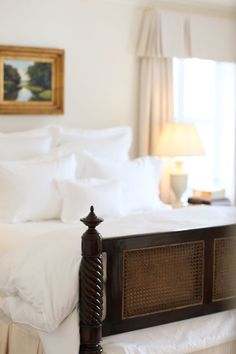 a bed with white sheets and pillows in a bedroom