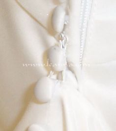 a close up of a white dress with beads on it